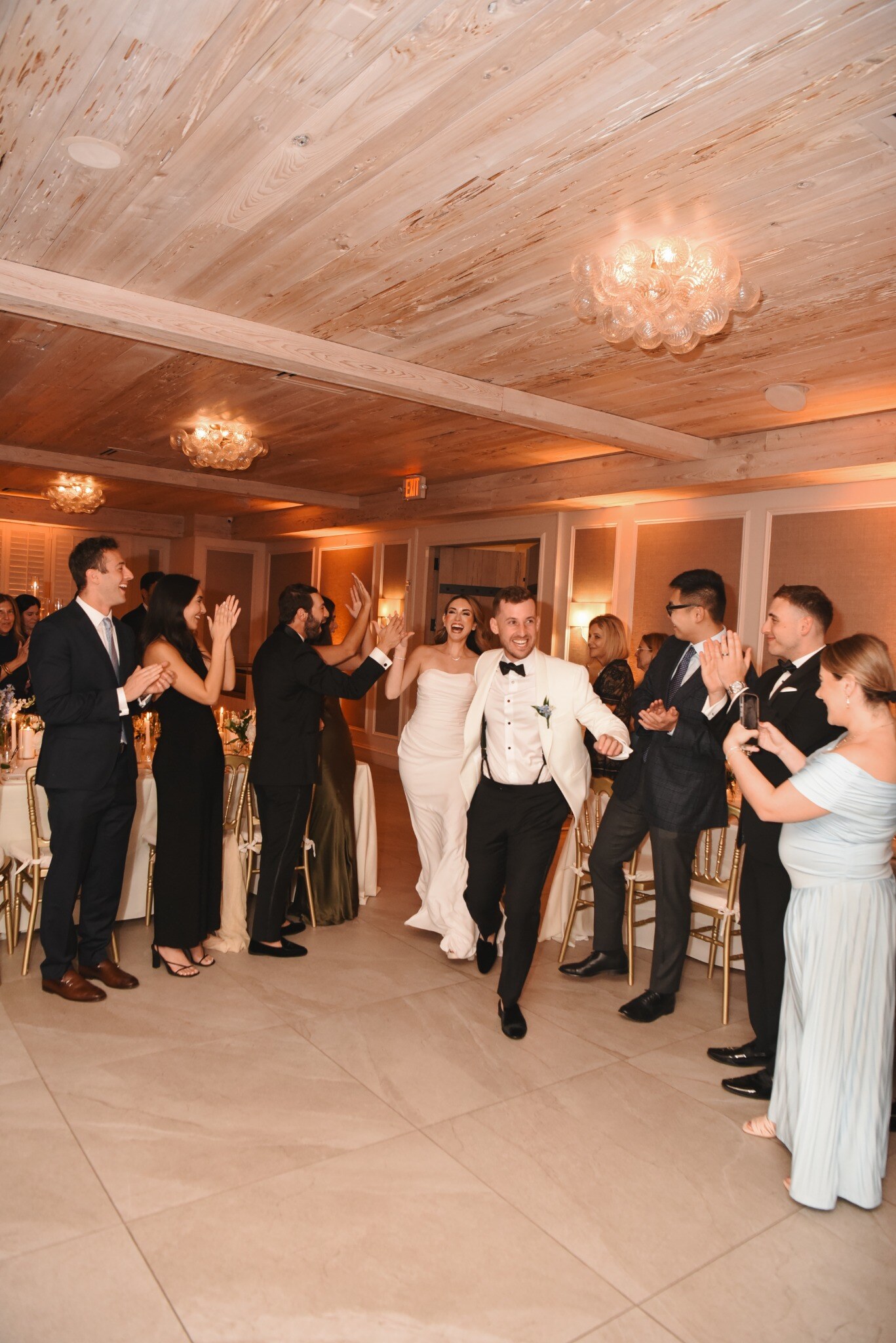 Newlyweds entering their reception surrounded by cheering guests